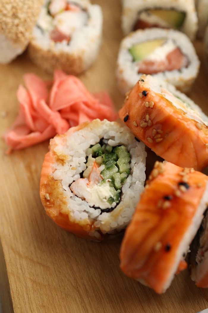 Close-up of delicious sushi rolls with rice, seafood, and sesame seeds on a wooden board.
