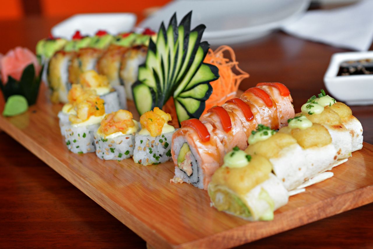 Colorful sushi platter featuring various rolls with decorative garnishes, showcasing culinary art.